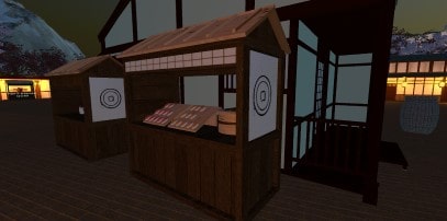 Screenshot in het donker van een kraampje met sushi en op de achtergrond verlichte huizen en een berg